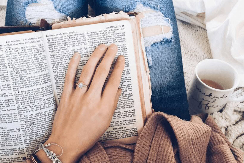 Picture of womans hand on Bible with a cup of coffee for post Bible journaling tips for beginners