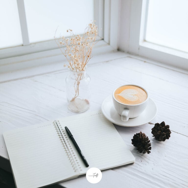 A cozy scene featuring an open notebook, pen, a cup of coffee with latte art, and dried flowers by a window