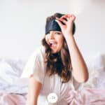 a woman lifting up a sleep mask and winking