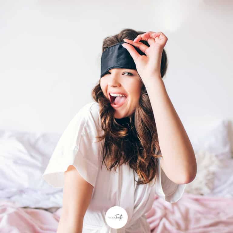 a woman lifting up a sleep mask and winking