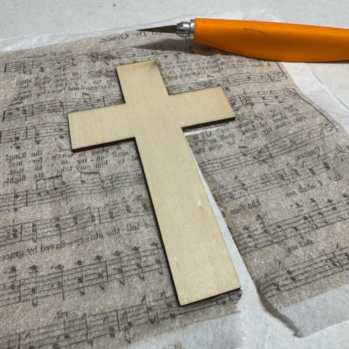 exacto knife trimming excess tissue paper for Christian decoupage craft project