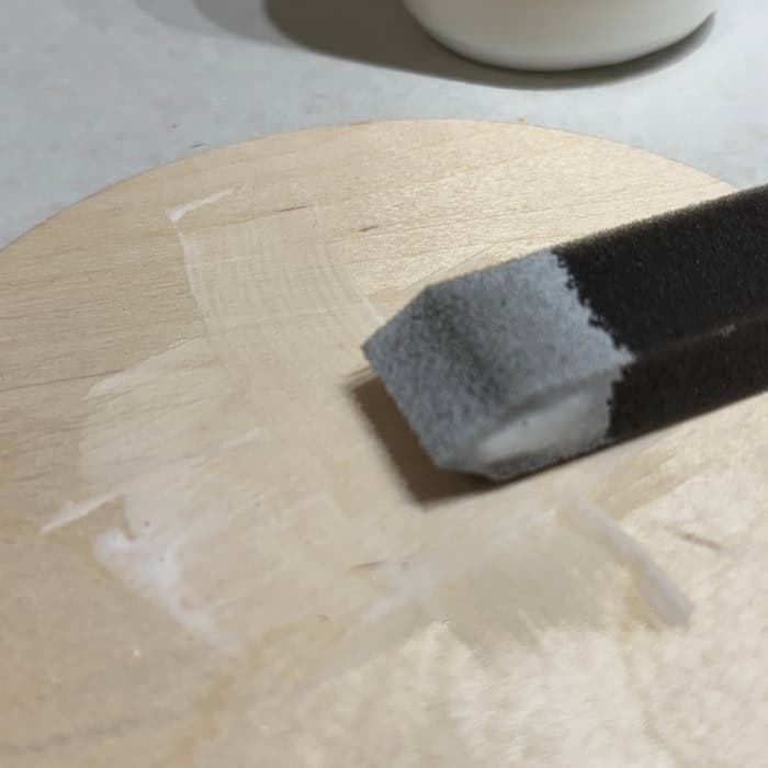foam brush coating with mod podge on wood circle for project using Christian Craft Papers