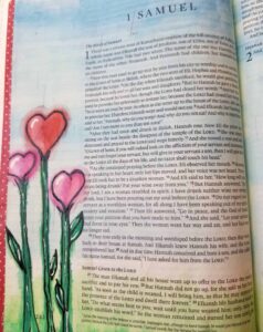 Bible Journaling Drawings: Simple & Beautiful Ways to Worship Through Art (Even If You’re Not an Artist) 26 Bible journaling page in 1 Samuel decorated with heart-shaped pink flowers and green stems painted along the margin, creating a whimsical and faith-inspired floral design